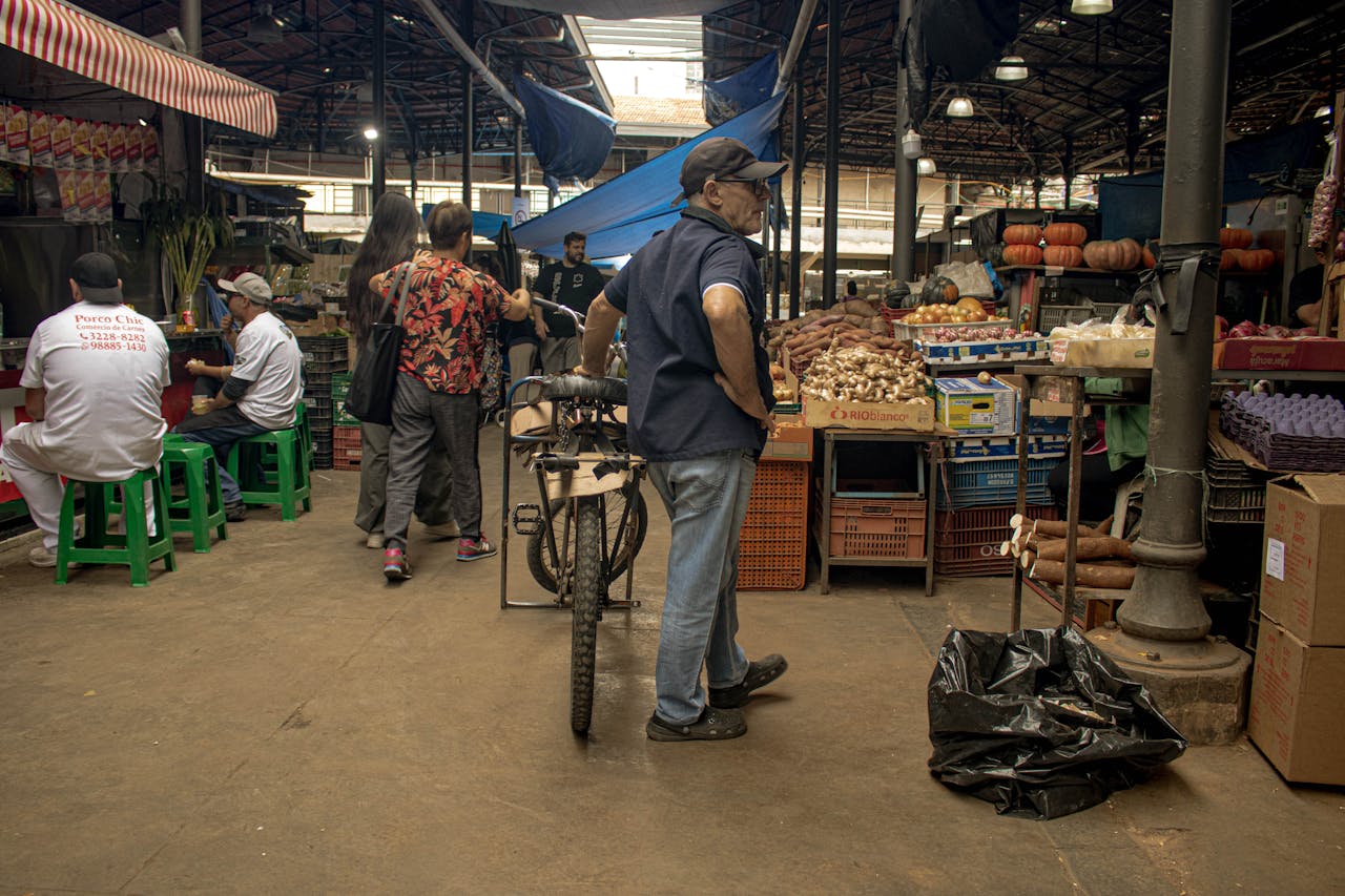 A vibrant indoor market with vendors and customers interacting amidst fresh produce and goods.